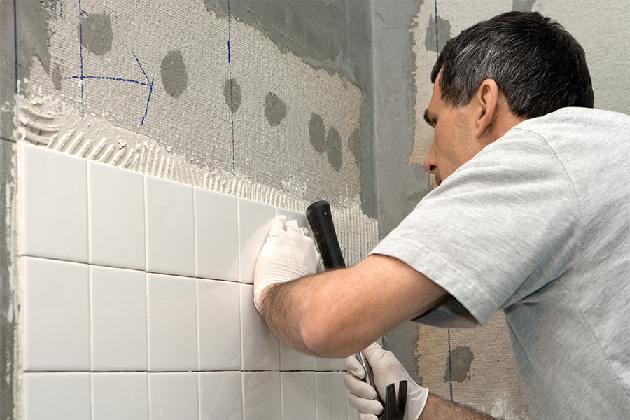 contractor installing new white tiles at bathroom walls