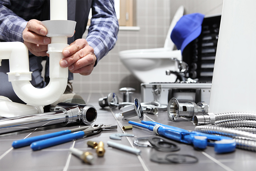 plumber hands close up holding pipes for installation at bathroom with tools on the floor san diego ca