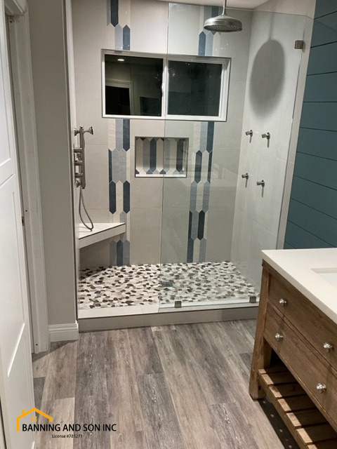 A mid-century modern shower is the focus of this image. It has modern shower fixtures and a wood-like floor to complete the bathroom remodel.