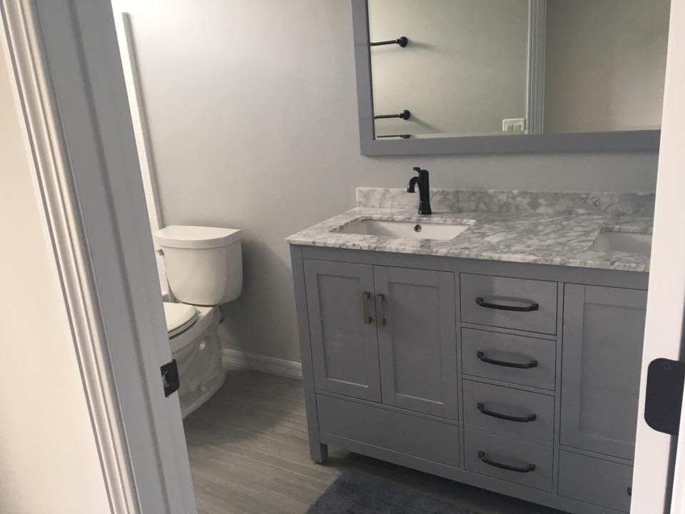 A gray bathroom with the new vanity as the main focus of the image. The new vanity has a double sink with a matte-black faucet and drawer pulls.