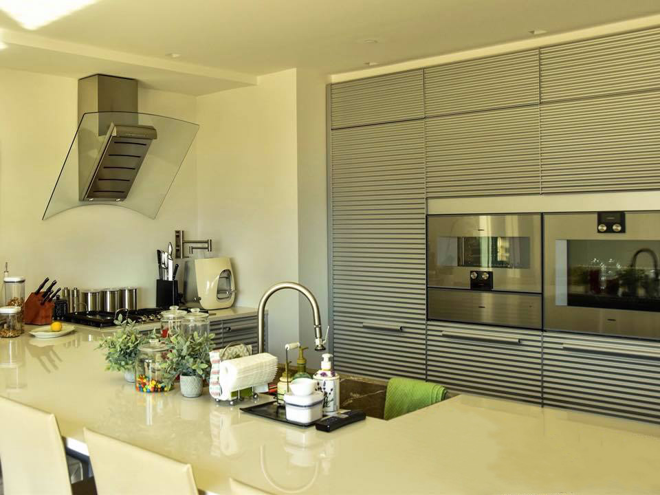 A contemporary kitchen with beige walls, shiny appliances and a large countertop island.