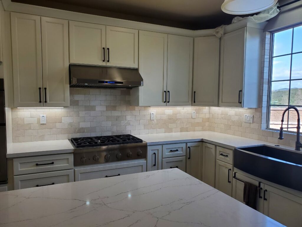 A kitchen with cream cabinets and white tile including the backsplash.