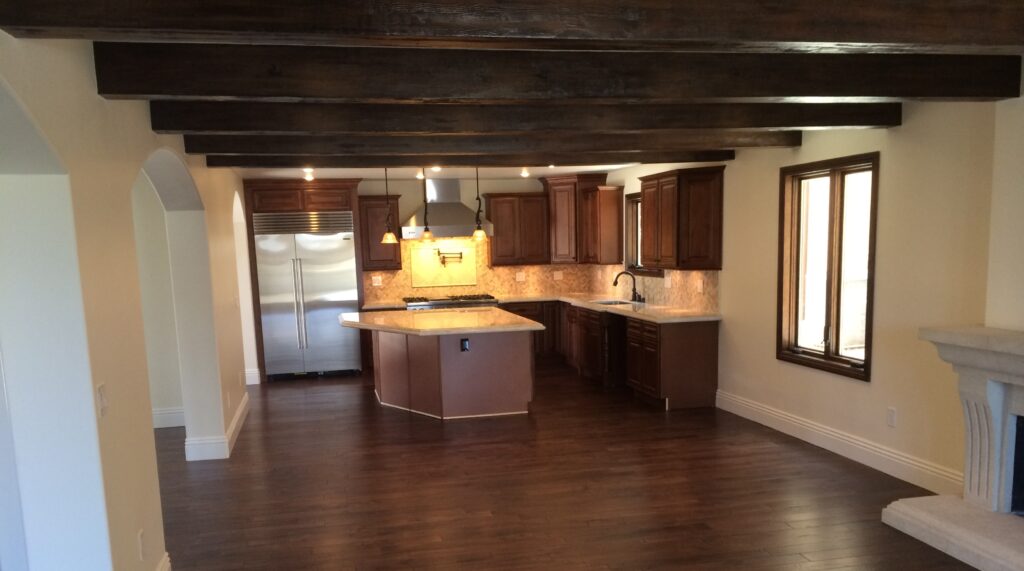 A dark wood kitchen with beige countertops, pendant lighting and dark hardwood floors.